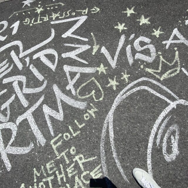 Farbenfrohes Schulchronik Bild mit bunten Kreidebuchstaben und Zeichnungen auf Asphalt.