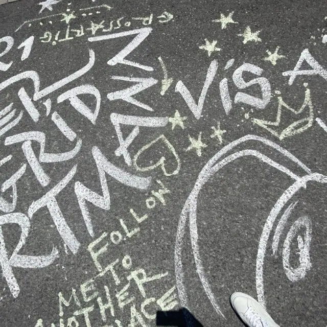 Farbenfrohes Schulchronik Bild mit bunten Kreidebuchstaben und Zeichnungen auf Asphalt.