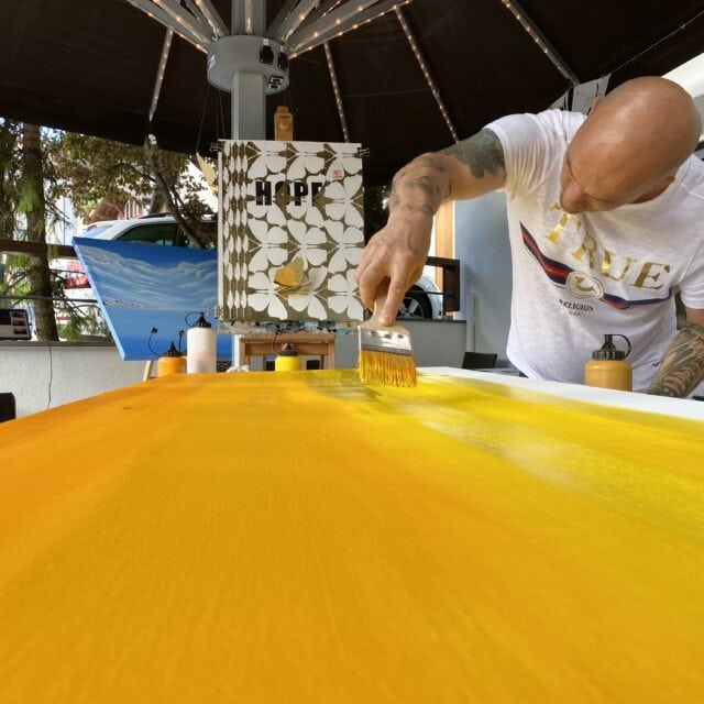 Mann malt große Leinwand gelb an.