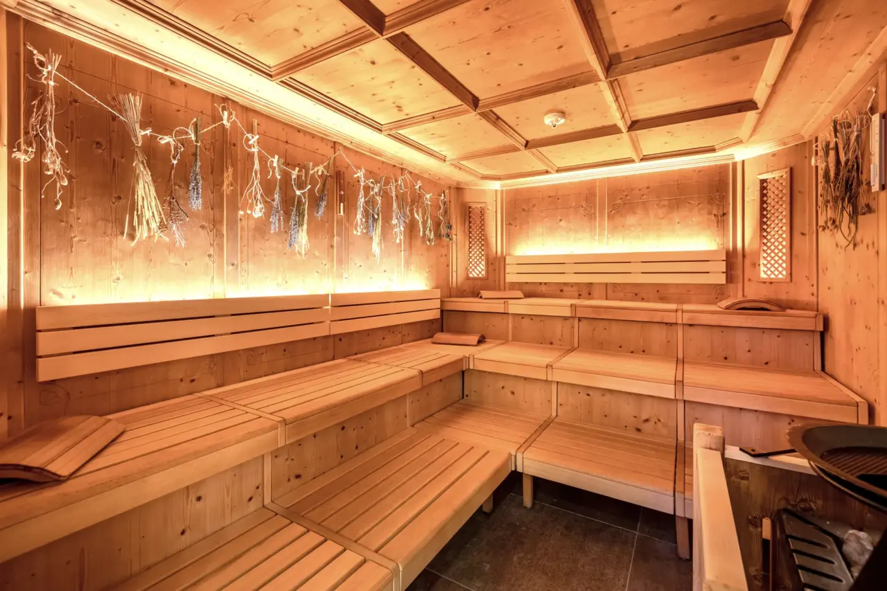 Leere Holzsauna mit Bänken und Bündel Kräuter
