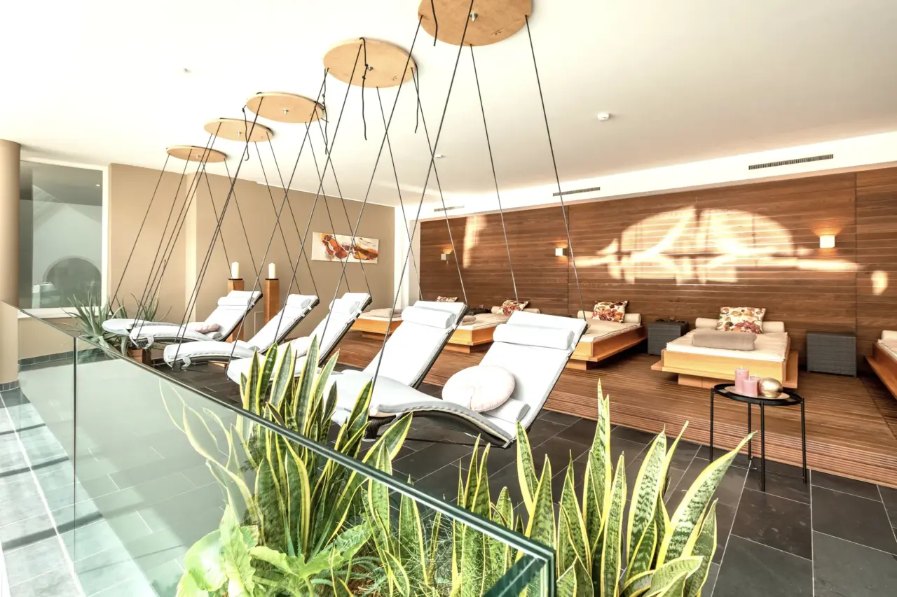 Moderne Wellness-Lounge mit Liegen und Pflanzen.