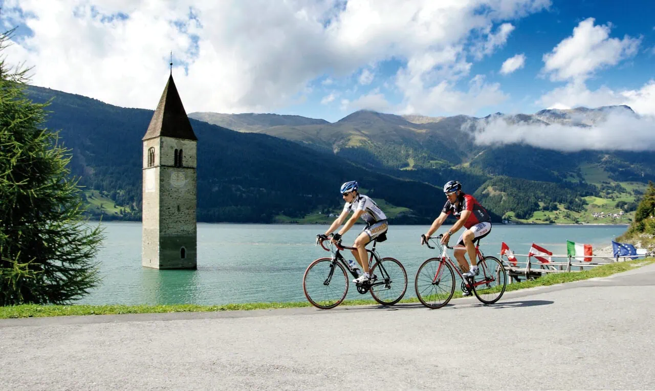 Radfahrer am Reschensee mit Kirchturm im Wasser