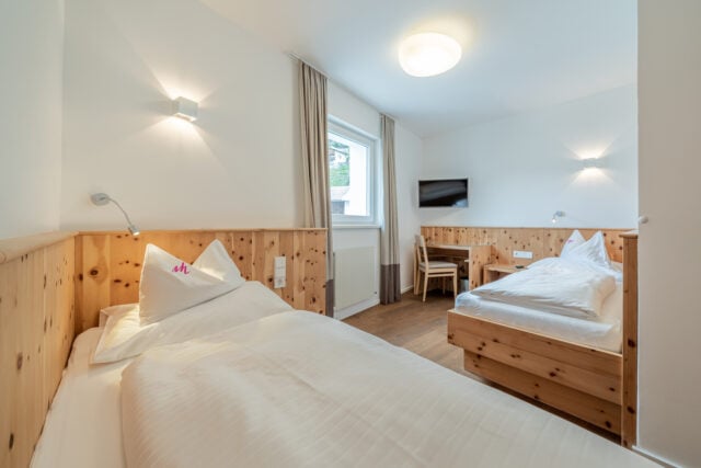 Gemütliches Doppelzimmer mit Holzmöbeln und Fernseher