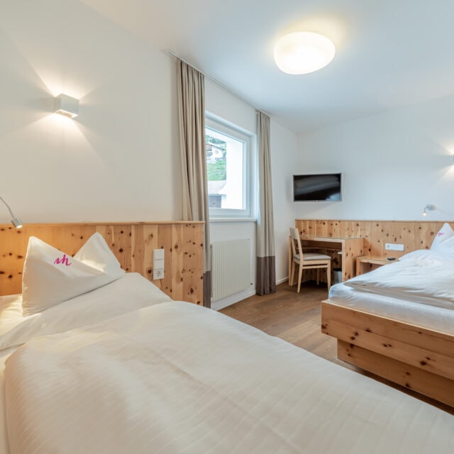 Gemütliches Doppelzimmer mit Holzmöbeln und Fernseher