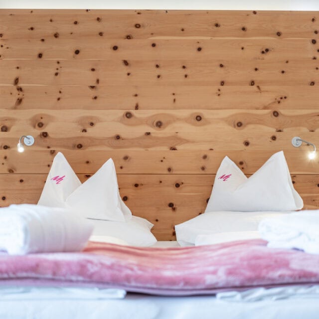 Gemütliches Doppelbett mit Holzrückwand und Bettwäsche.