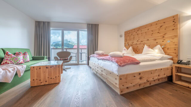 Helles Hotelzimmer mit Holzdetails und Bergblick