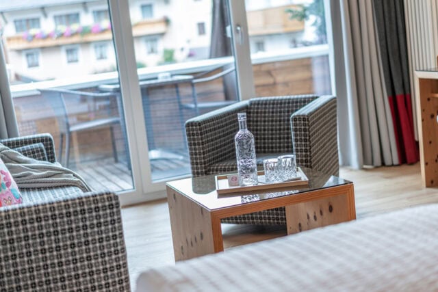 Durchblick auf Balkon mit Glasfront und Sitzmöbel im Naudererhof in Tirol.