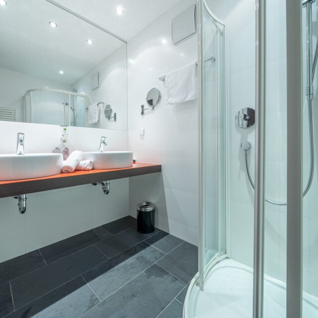 Sauberes Badezimmer mit Doppelwaschbecken und Dusche im Naudererhof, Tirol.
