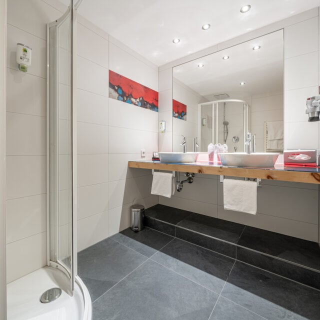 Modernes Badezimmer mit Dusche und großem Spiegel