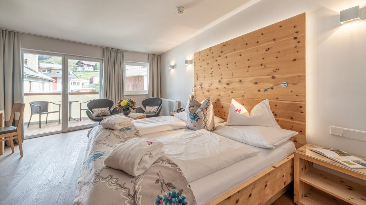 Gemütliches Hotelzimmer mit Holzmöbeln und Balkonansicht.