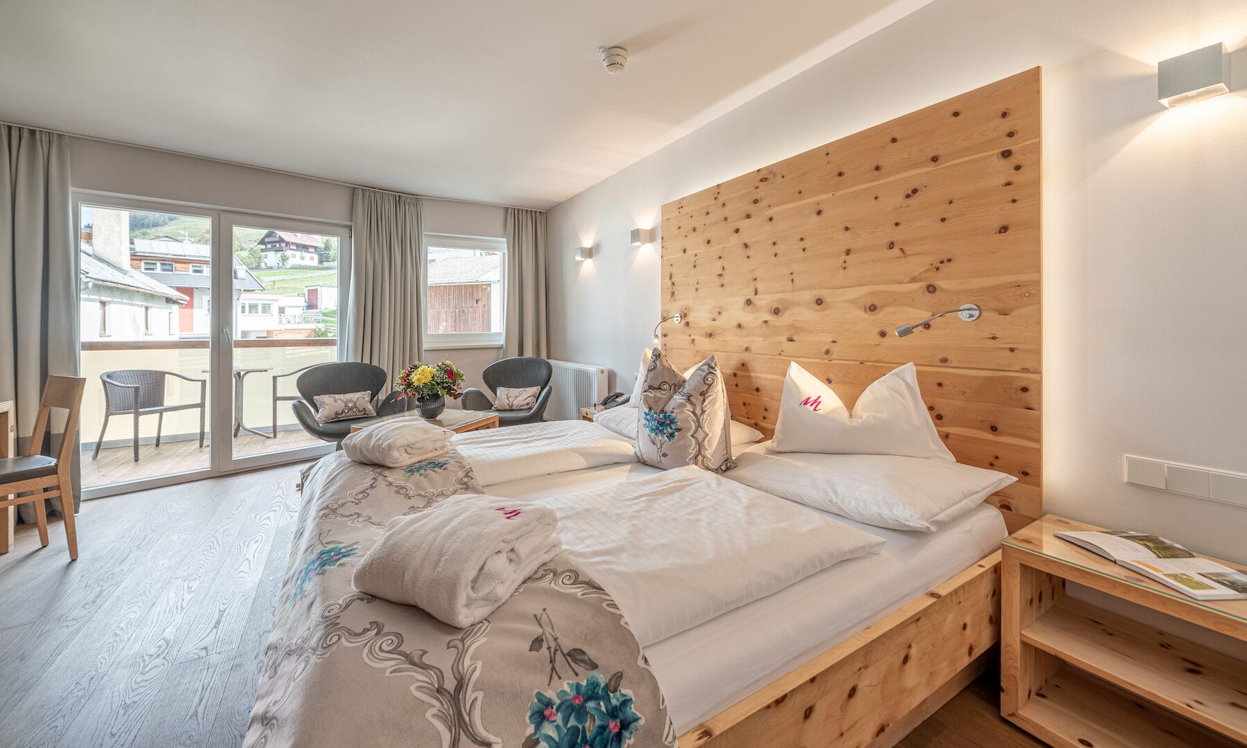 Gemütliches Hotelzimmer mit Holzmöbeln und Balkonansicht.