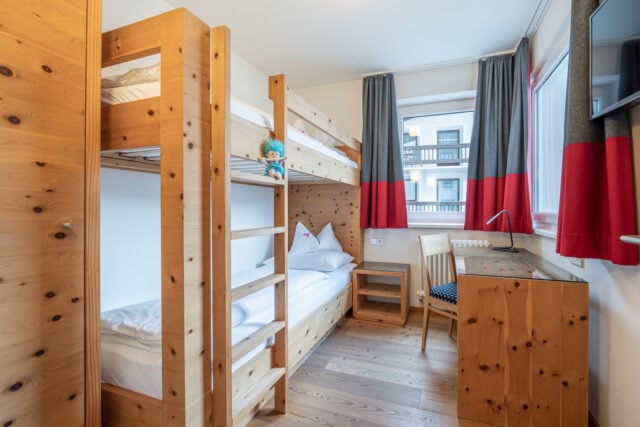 Gemütliches Kinderzimmer mit Hochbett und Schreibtisch.