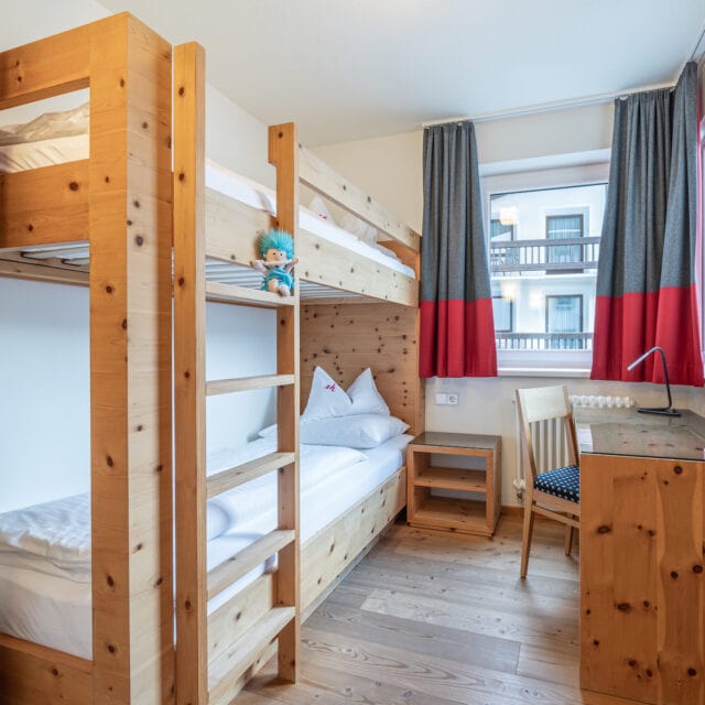 Gemütliches Kinderzimmer mit Hochbett und Schreibtisch.