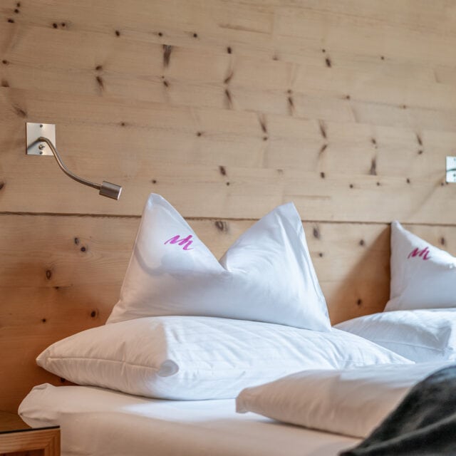 Doppelbett mit Holzrückwand und Kissen