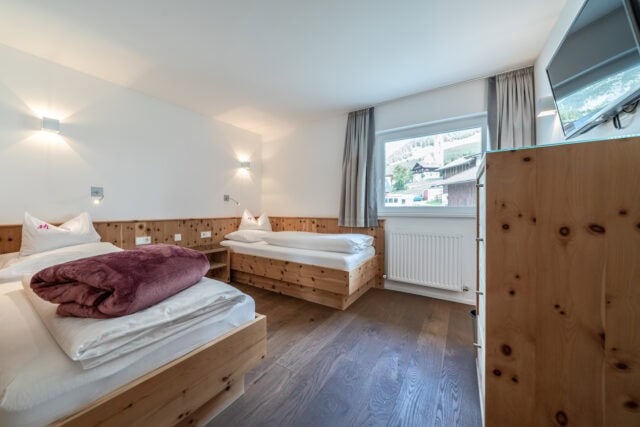 Helles Schlafzimmer mit Holzbetten und Fensterblick.