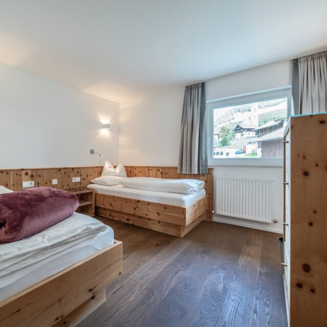Helles Schlafzimmer mit Holzbetten und Fensterblick.