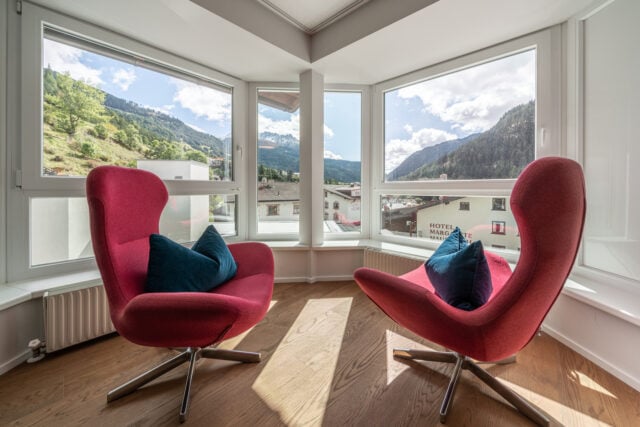 Zwei rote Sessel mit Bergblick durch Fenster.