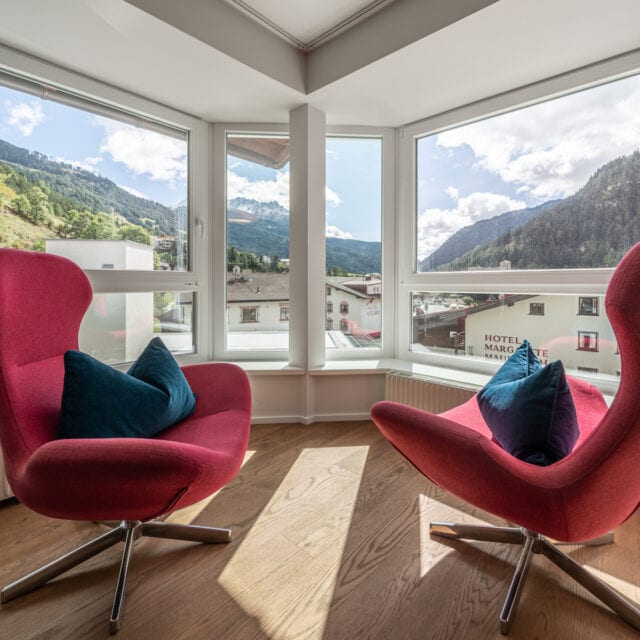 Zwei rote Sessel mit Bergblick durch Fenster.