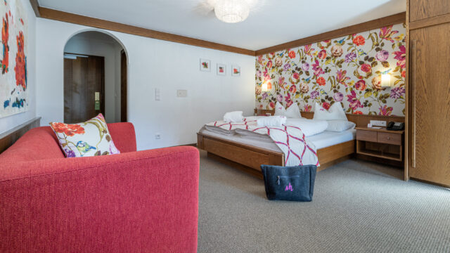 Hotelzimmer mit Bett und rotem Sofa