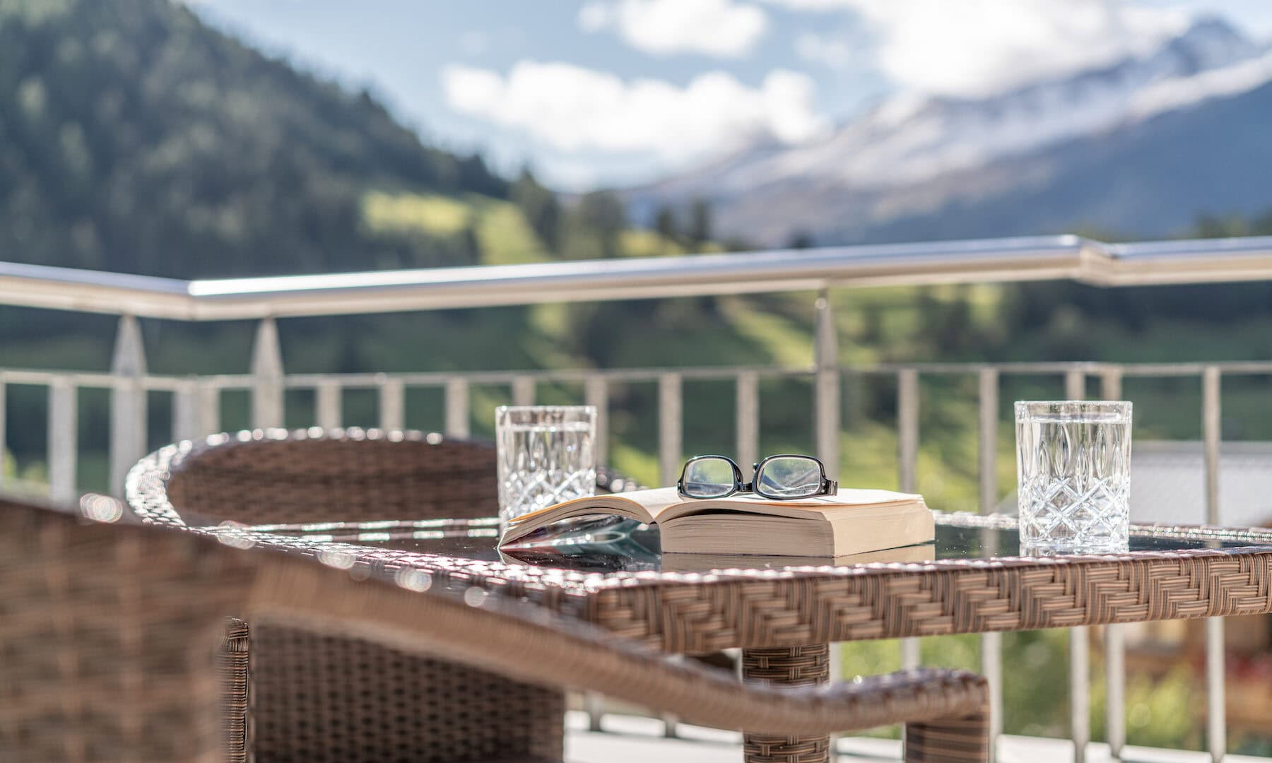 Terrasse mit Buch, Brille und Wassergläsern