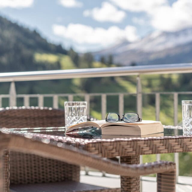 Terrasse mit Buch, Brille und Wassergläsern
