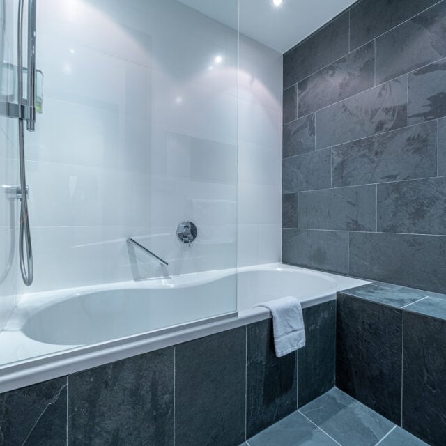 Modernes Badezimmer mit Badewanne und grauen Fliesen