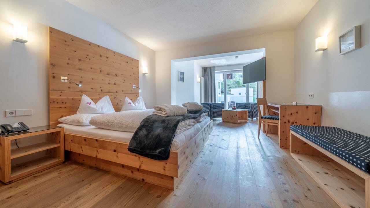 Gemütliches Hotelzimmer im Naudererhof mit Holzdesign und Balkonblick.