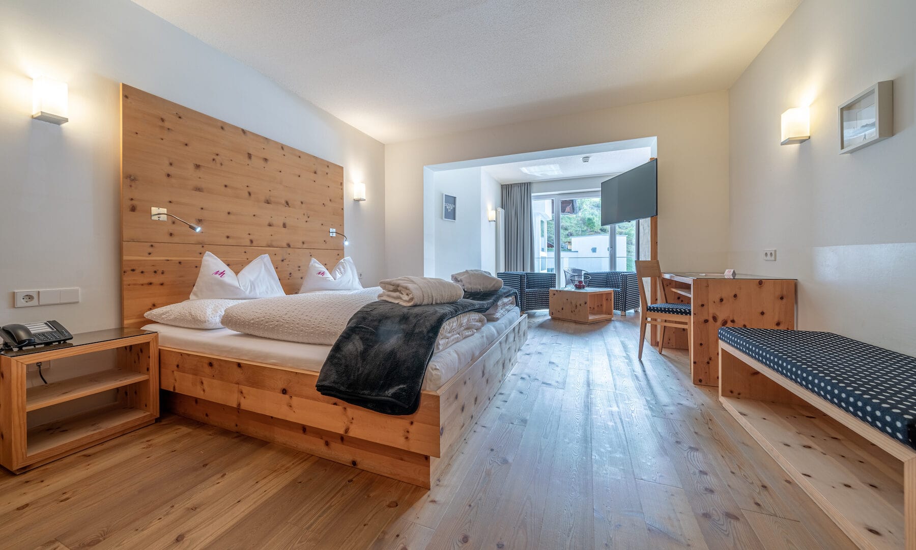 Gemütliches Hotelzimmer im Naudererhof mit Holzdesign und Balkonblick.