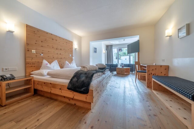 Gemütliches Hotelzimmer im Naudererhof mit Holzdesign und Balkonblick.