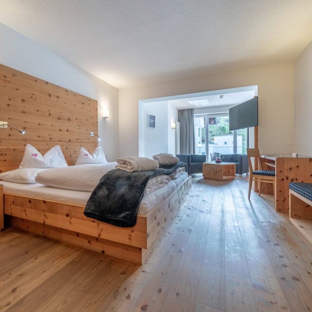 Gemütliches Hotelzimmer im Naudererhof mit Holzdesign und Balkonblick.