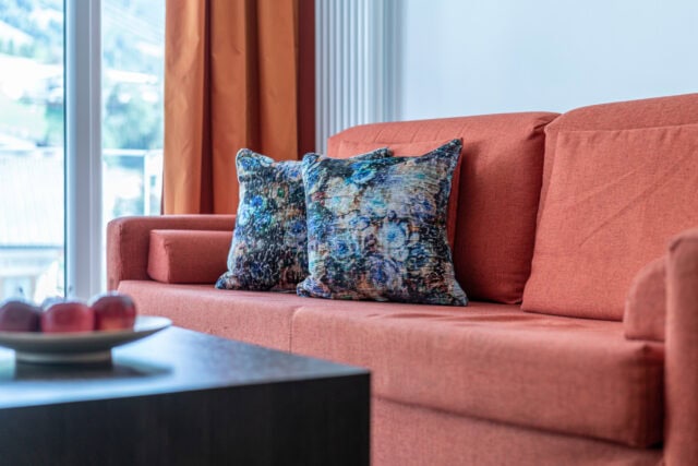 Rotes Sofa mit gemusterten Kissen im Wohnzimmer.