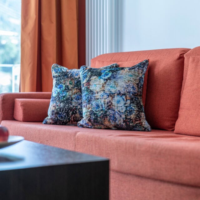 Rotes Sofa mit gemusterten Kissen im Wohnzimmer.