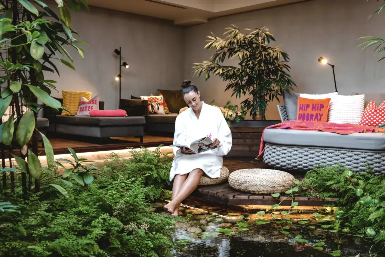 Bequeme Lounge im stilvollen Hotelbereich mit Pflanzen und Wasseranlage.