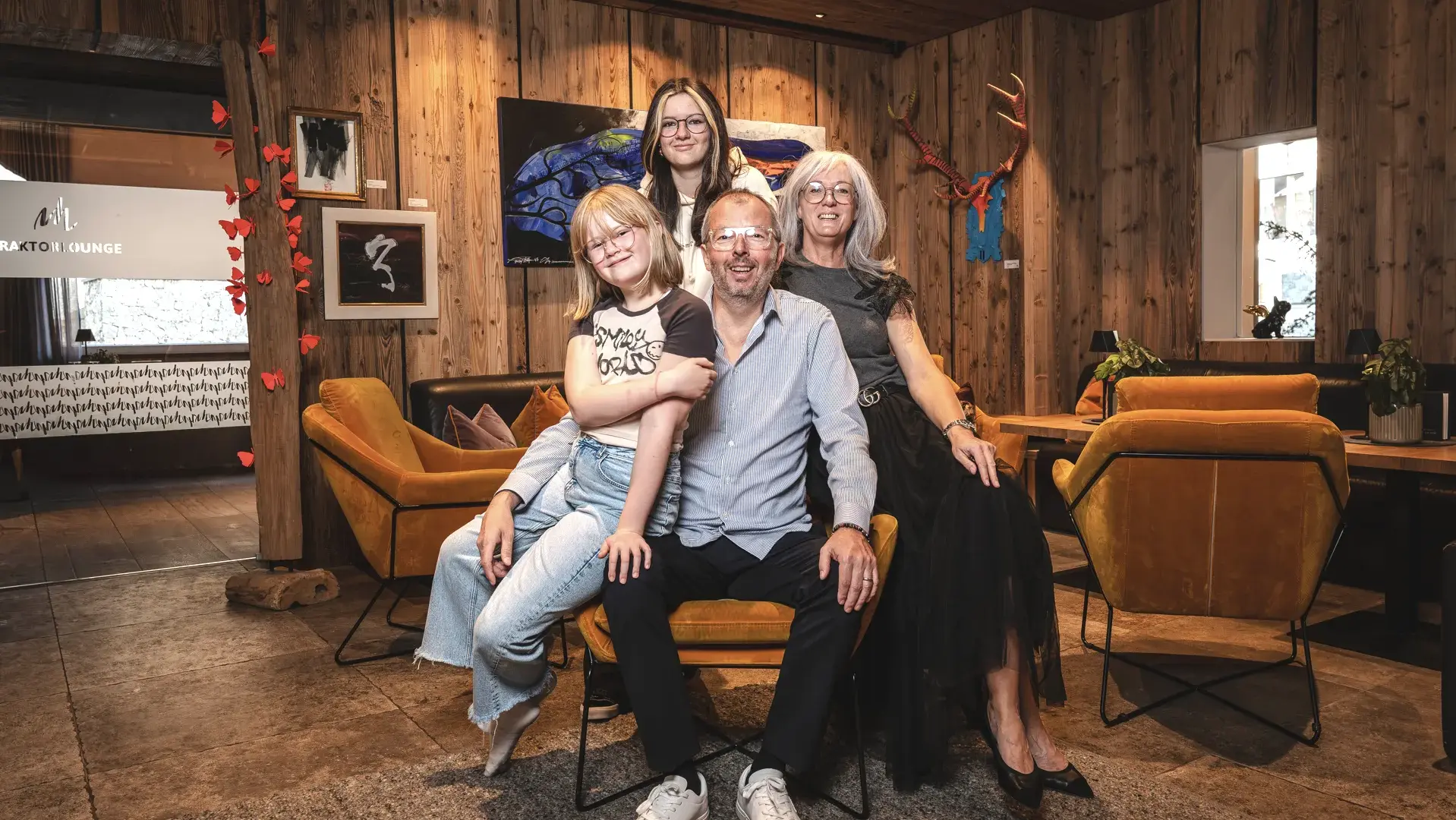 Familie posiert im Wohnzimmer vor Holzverkleidung.