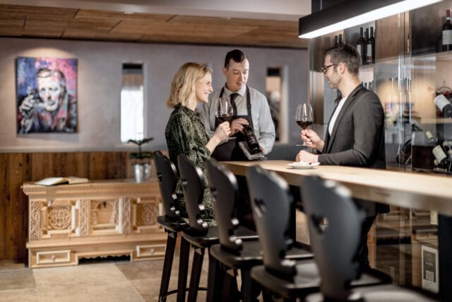 Weinprobe mit drei Personen an der Theke.