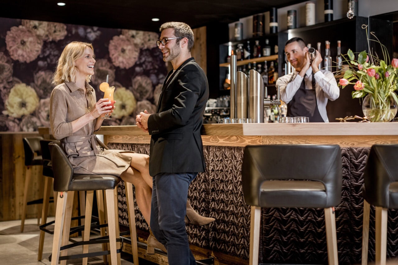 Lächelnde Menschen an einer Bar mit Cocktails.