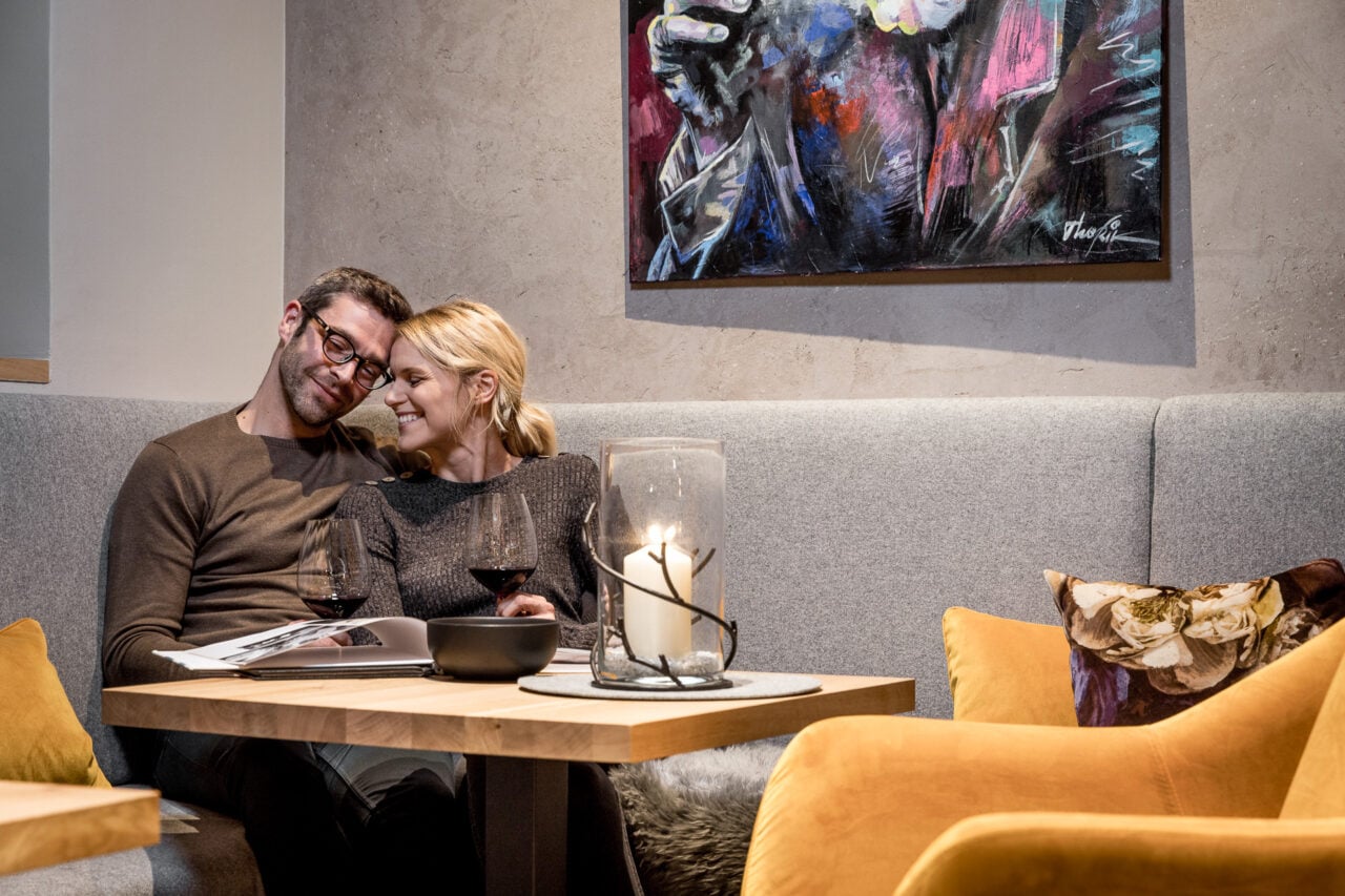 Paar entspannt auf Sofa mit Weinglas und Kerze.