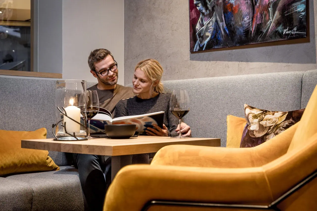 Pärchen liest im gemütlichen Wohnzimmer.
