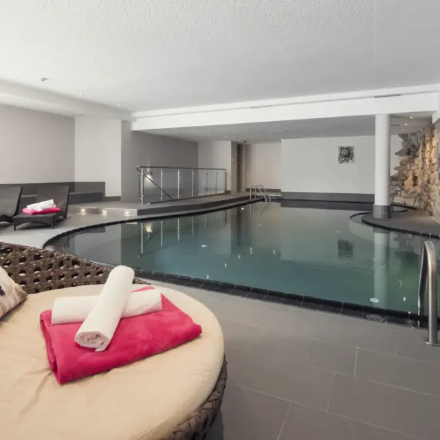 Eleganter Innenpool mit Liegestühlen und Handtüchern.