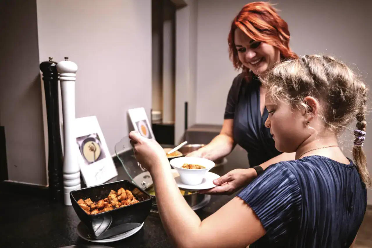 Frau und Mädchen servieren Essen am Buffet.