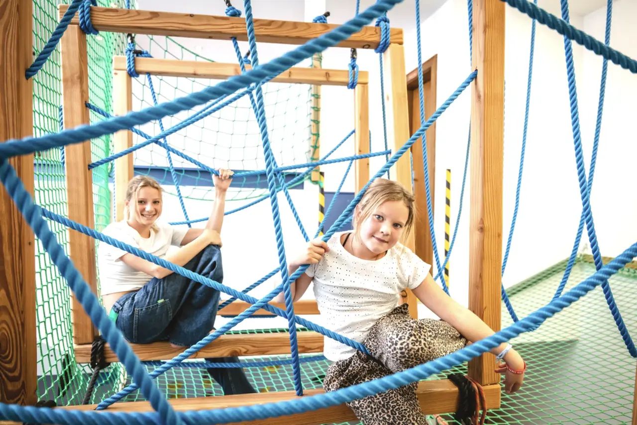 Kinder klettern auf Seilstruktur im Innenraum