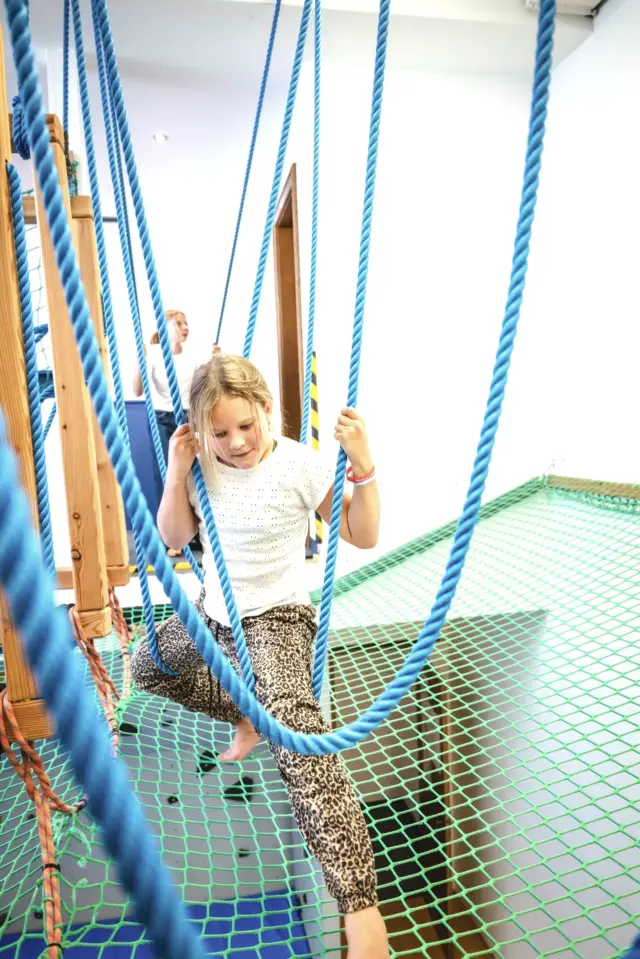 Kind klettert auf Netz und Seilen