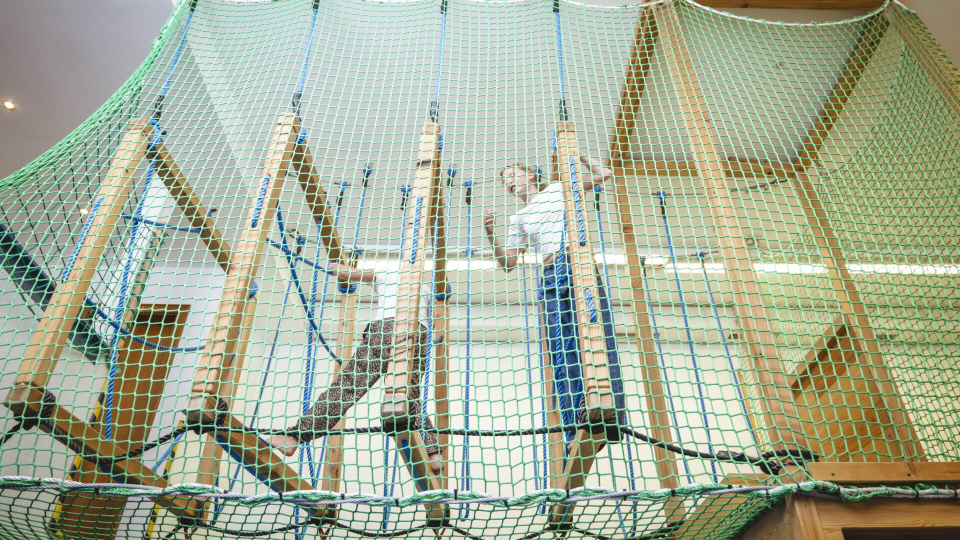 Kinder im Indoor-Klettergerüst aus Holz und Seilen