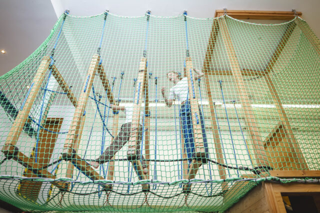 Kinder im Indoor-Klettergerüst aus Holz und Seilen