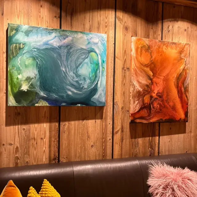 Bunte Gemälde an Holzwand über Sofa mit Kissen.