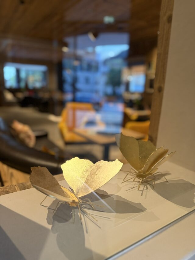 Goldene Schmetterlingsdekoration auf weißer Fläche.