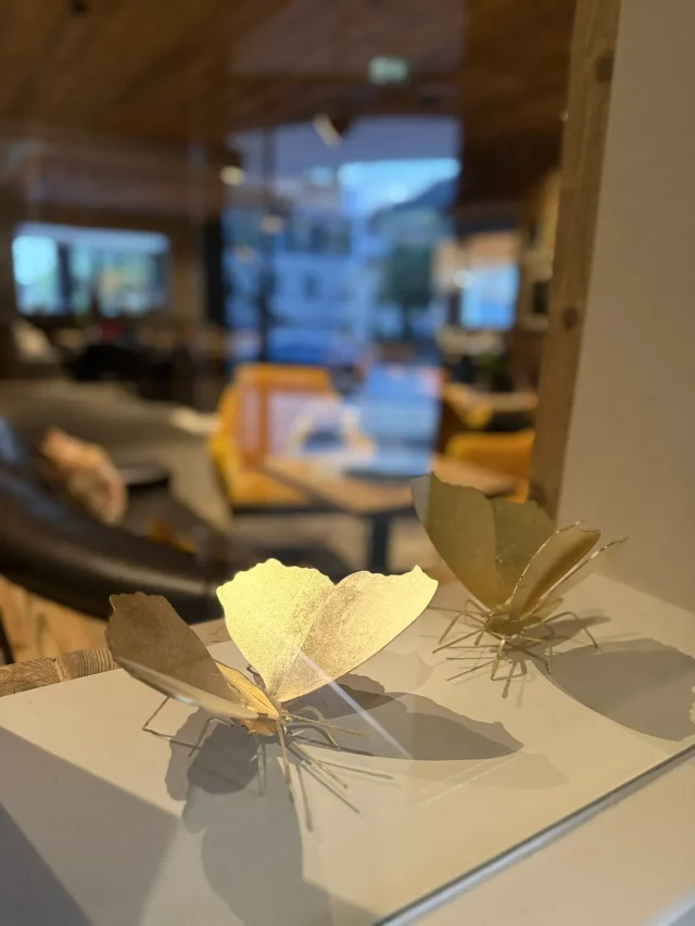 Goldene Schmetterlingsdekoration auf weißer Fläche.