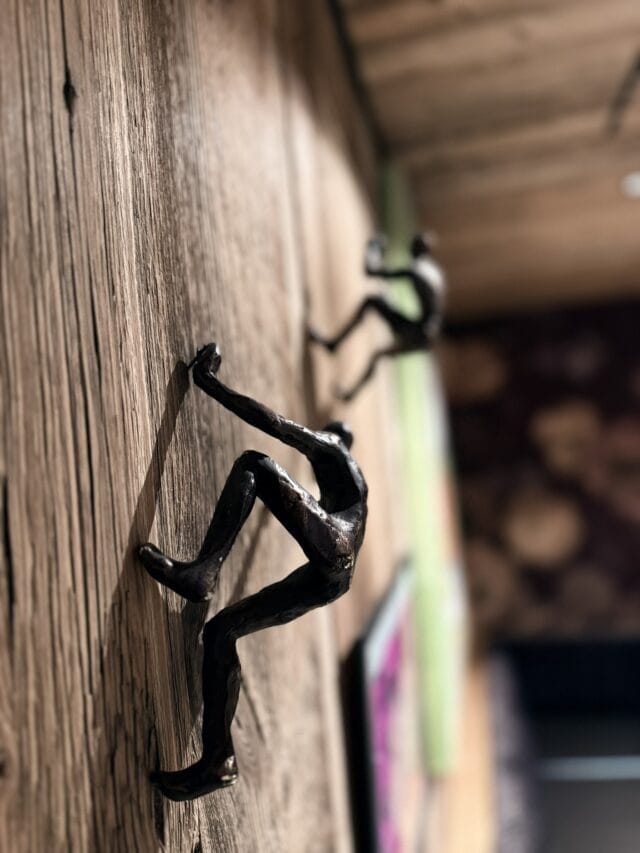 Metallfiguren klettern Holzwand hoch