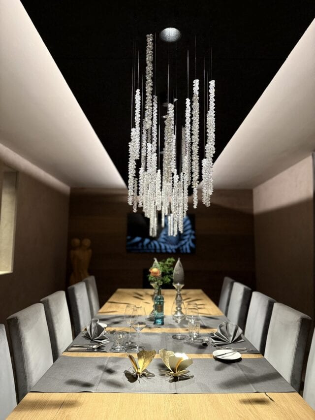 Elegantes Esszimmer mit Kronleuchter und gedecktem Tisch.