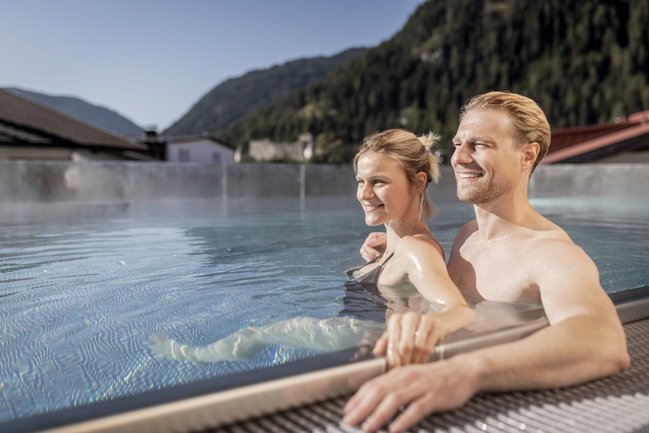 Paar genießt Pool mit Bergblick.